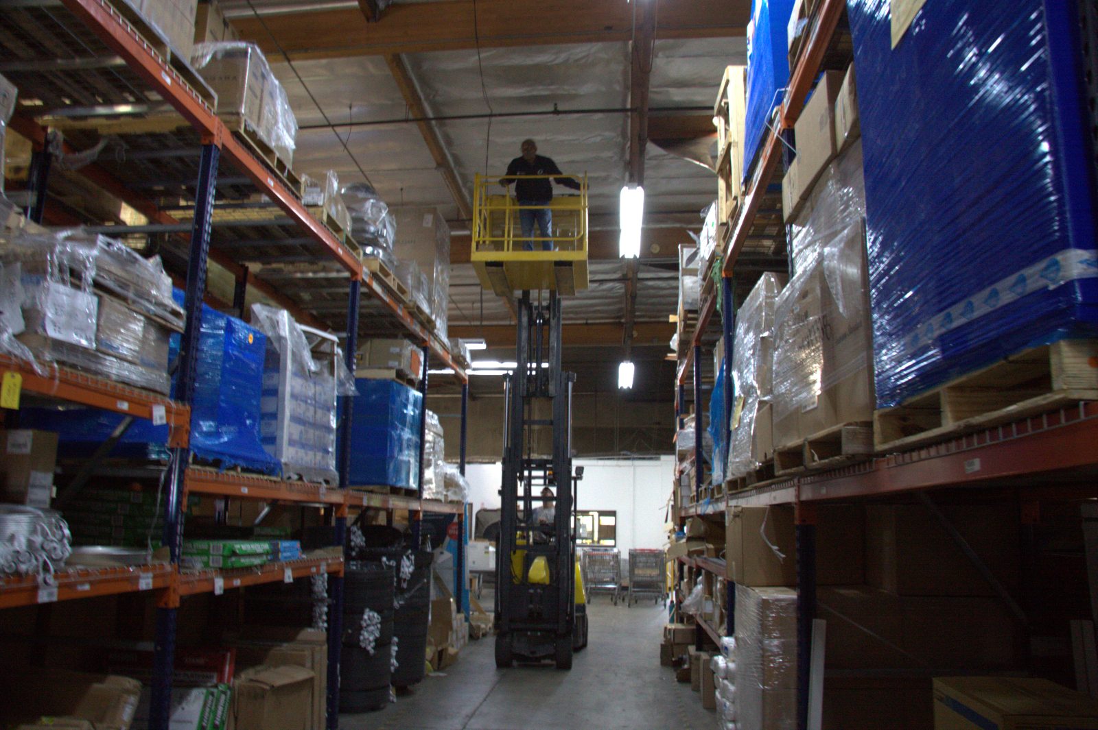 OSSUM IT technician on a lift running cable for a camera or wireless access point in a warehouse